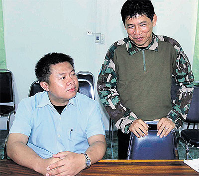 Suriyon Pothibandit, left, assistant to Kaeng Krachan National Park chief Chaiwat Limlikitauksorn, right, surrenders to police, who want him in connection with the recent burning of a wild elephant carcass in the park.