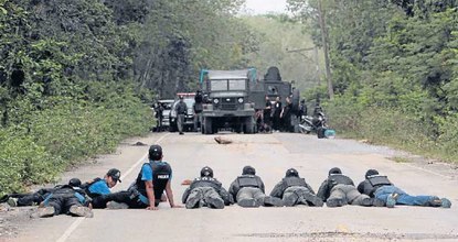 Police officers and soldiers take up position during a search for explosives in Ban Raman after local farmers alerted them to suspicious activities in Yala province Tuesday. REUTERS