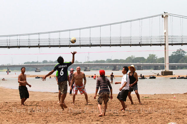 A group of locals enjoy a game of volleyball on the waterbed of the dried out Ping River in Tak province.