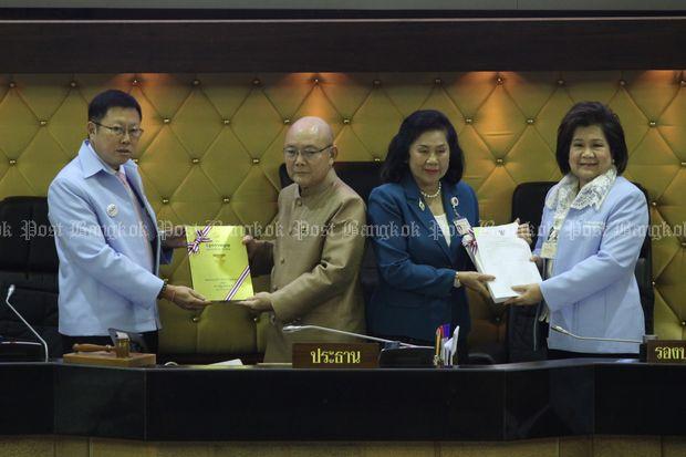 Constitution Drafting Committee chairman Borwornsak Uwanno (left) presents the only hardcover copy of the charter draft to NRC chairman Thienchay Kiranandana at Parliament on Saturday. As well, Nareewan Chintakanond (right), a CDC vice-chairwoman, presents a copy to her NRC counterpart, Tassana Boontong. (Photo by Thiti Wannamontha)