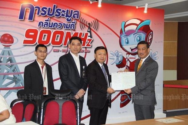 Takorn Tantasith (second right) secretary-general of the National Broadcasting and Telecommunications Commission (NBTC), accepts the application from Suthichai Cheunchoosil, AIS senior vice-president for business relations and development, for AIS to be the lone bidder at next week's restart of the last 4G auction. (Bangkok Post photo)